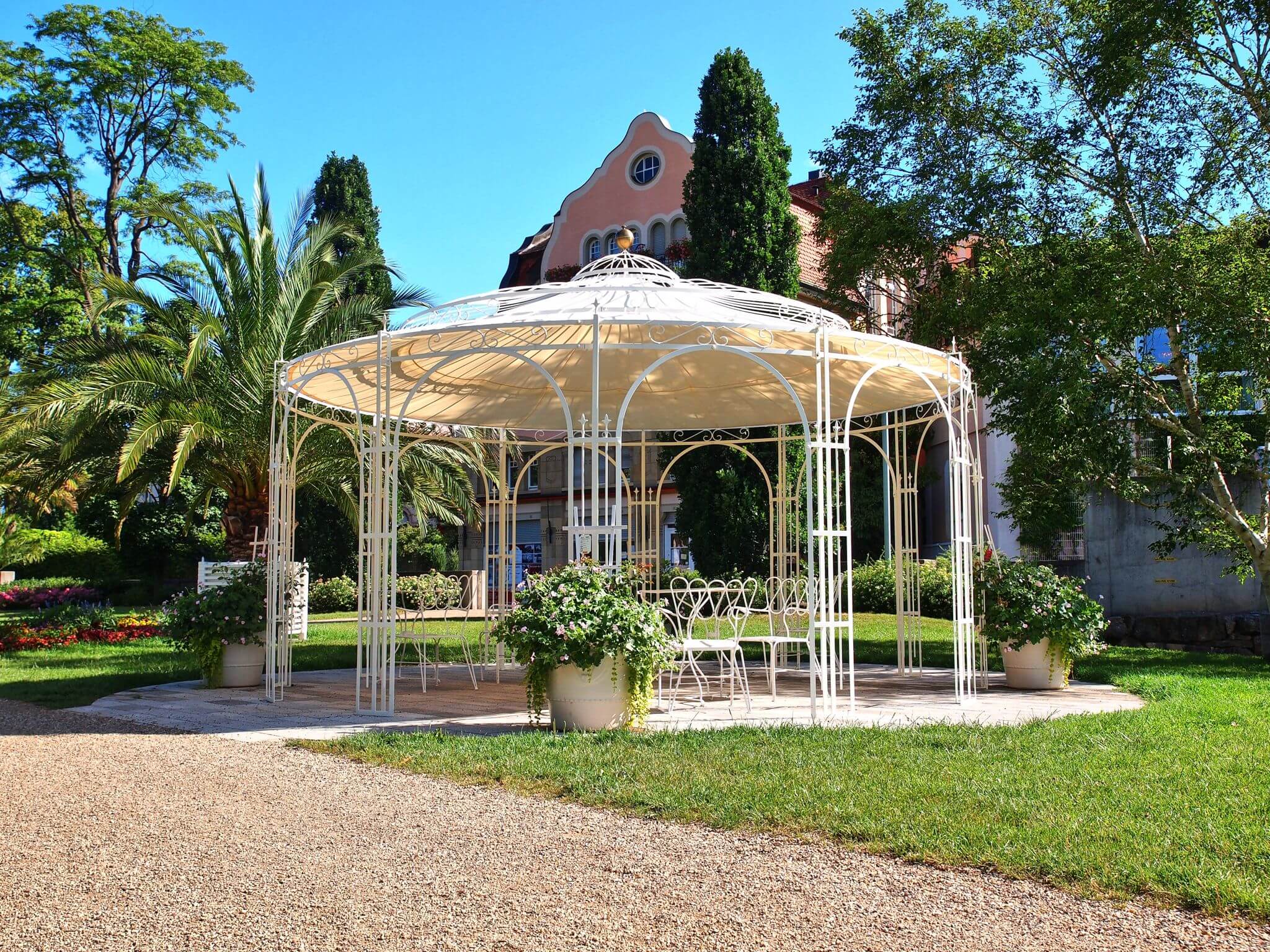 Pavillon Toskana in pulverbeschichteter Sonderfarbe weiss mit Sonnensegel und Messingkugel in einem Park