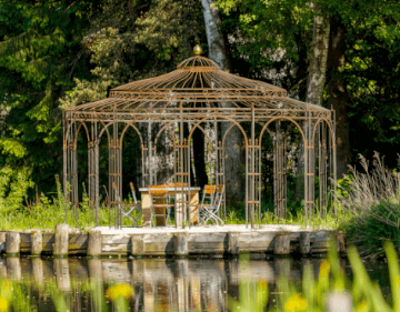 Pavillon Toskana in unbeshichtet mit Holzmoebeln hinter einem Teich