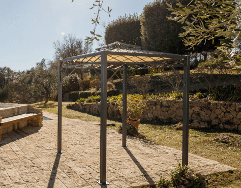 Pavillon Bolzan in pulverbeschichteter Ausführung mit Sonnensegel auf einer Steinterrasse im Frühling