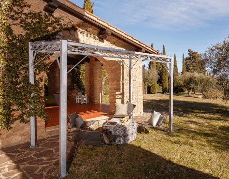 Pergola Ischia in feuerverzinkter Ausführung mit Sonnensegel an Terrasse angestellt mit Sitzgelegenheiten zum Entspannen
