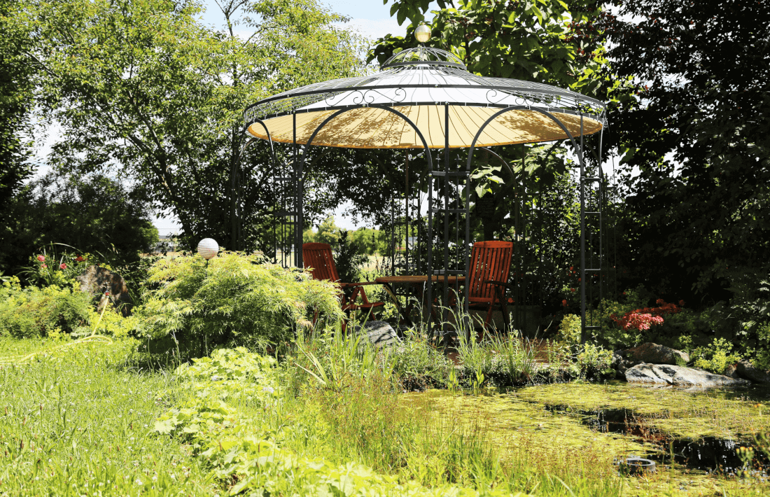 Pavillon Florenz pulverbeschichtet anthrazit mit Sonnensegel und Messingkugel an einem Teich im Garten