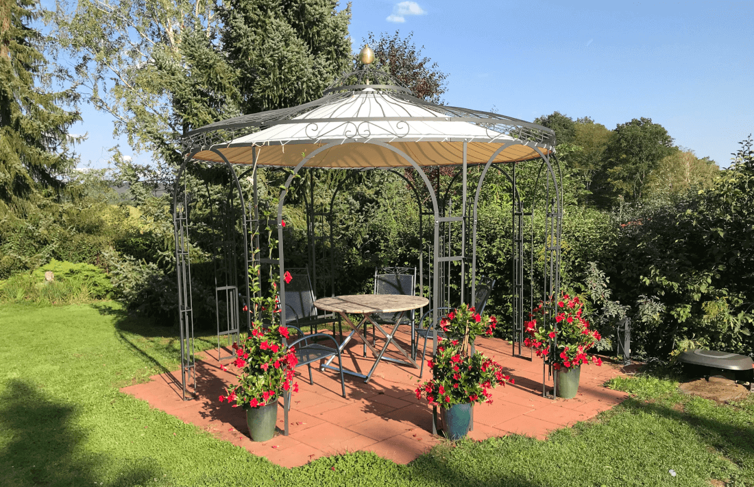 Pavillon Florenz pulverbeschichtet moosgruen mit Sonnensegel und Messingkugel bei einer Sitzecke
