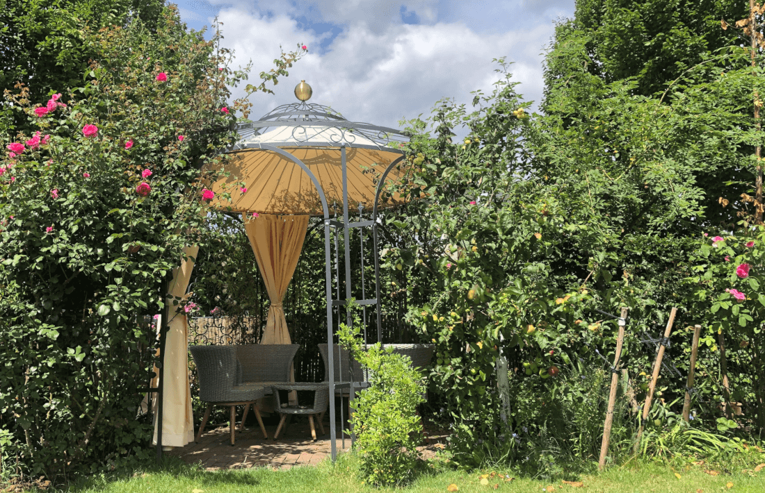 Pavillon Florenz pulverbeschichtet anthrazit mit Sonnensegel und Messingkugel bei einer Sitzecke in einem gruenen Garten
