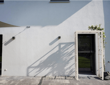 Rosenbogen Sorrento in pulverbeschichtet cremeweiss vor einem modernen Haus